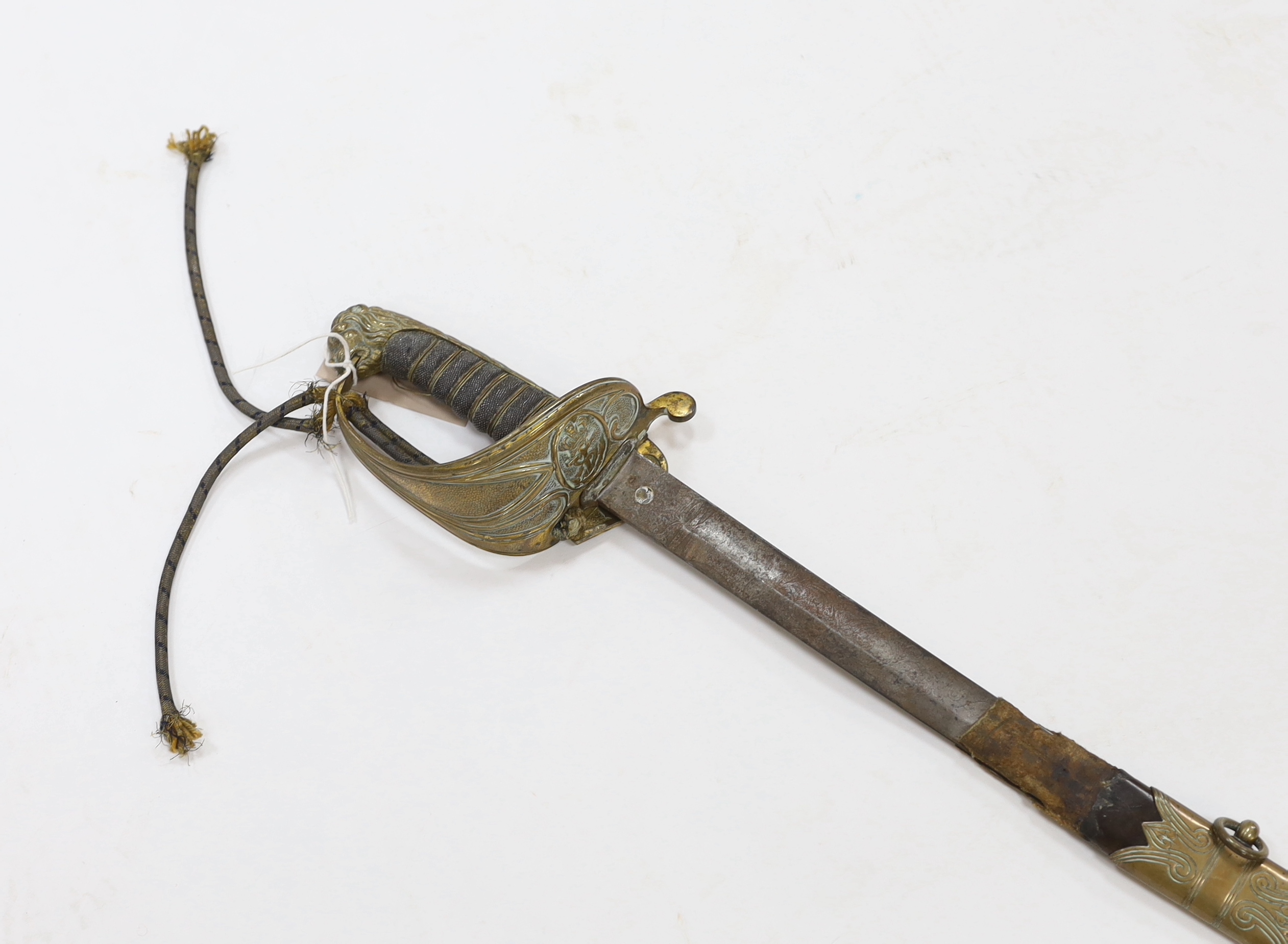 A late Victorian naval officer’s sword with regulation brass hilt, lion head pommel and blade etched with crown, VR and fouled anchor in its leather scabbard, top mount missing, blade 77cm